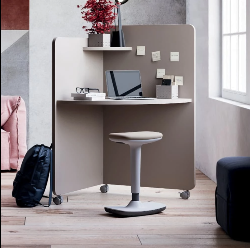 Stanowisko Home Office typu "kapsuła": mobilne biurko z przegrodą i kółkami, szary taboret ergonomiczny, laptop, lampka i roślina ozdobna w nowoczesnej aranżacji.